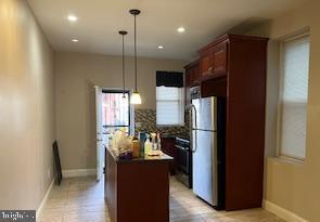 kitchen with a center island, decorative light fixtures, stainless steel fridge, and stove