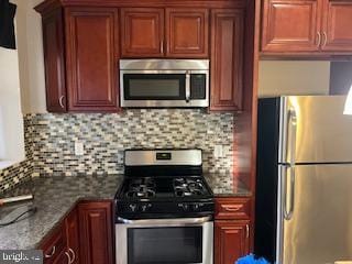 kitchen with decorative backsplash, dark stone countertops, and appliances with stainless steel finishes