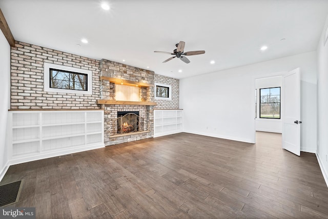 unfurnished living room featuring ceiling fan, dark hardwood / wood-style floors, a fireplace, and brick wall