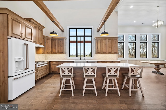 kitchen featuring decorative backsplash, beam ceiling, white fridge with ice dispenser, and a kitchen breakfast bar