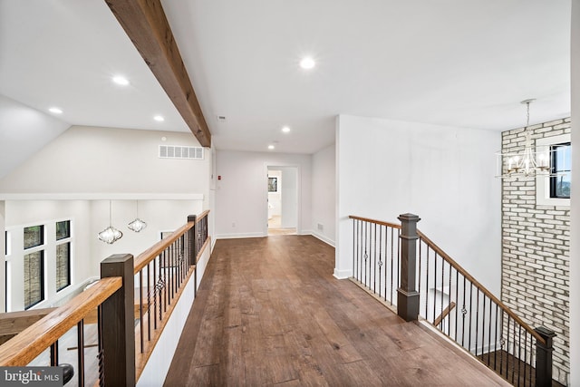 corridor with hardwood / wood-style flooring, beamed ceiling, and a notable chandelier