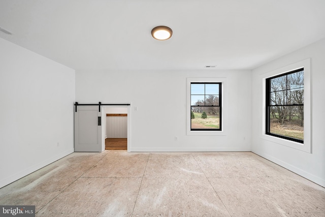 spare room with plenty of natural light and a barn door