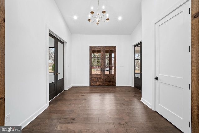 entryway with an inviting chandelier, dark hardwood / wood-style flooring, vaulted ceiling, and french doors