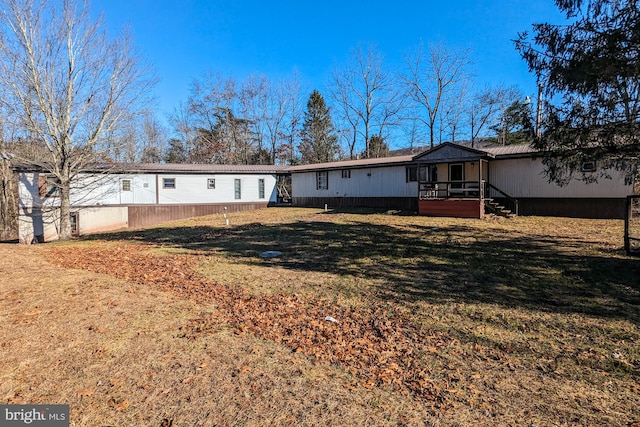 rear view of house featuring a wooden deck and a yard