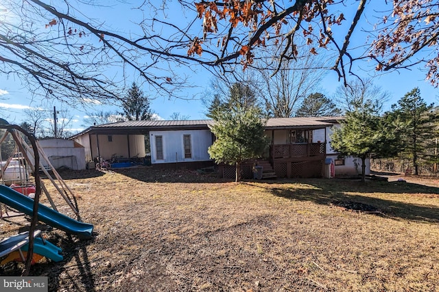 rear view of house with a playground and a wooden deck