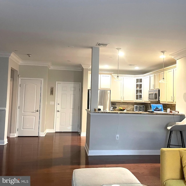 kitchen featuring white cabinets, crown molding, hanging light fixtures, kitchen peninsula, and stainless steel appliances