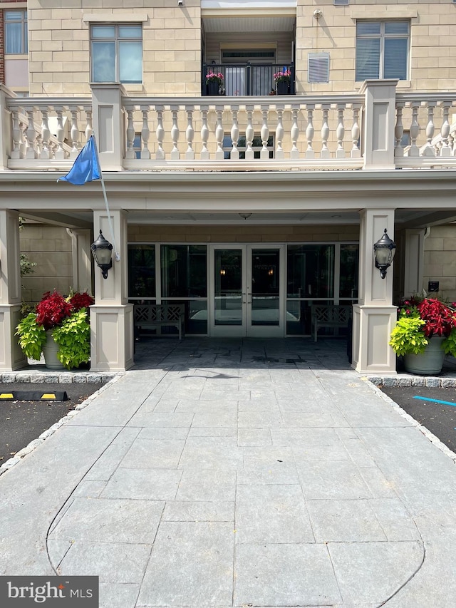 view of exterior entry featuring a balcony and french doors