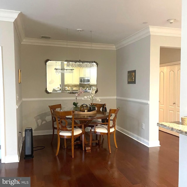 dining area with dark hardwood / wood-style floors, crown molding, and a chandelier