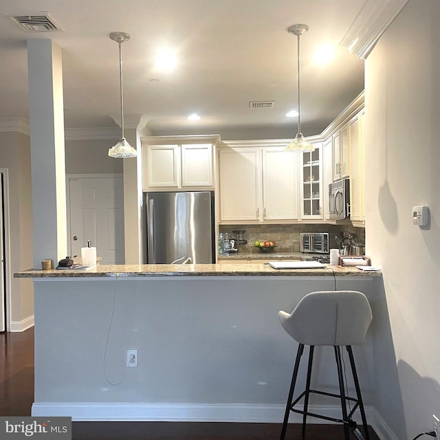 kitchen featuring hanging light fixtures, white cabinetry, light stone counters, kitchen peninsula, and stainless steel appliances