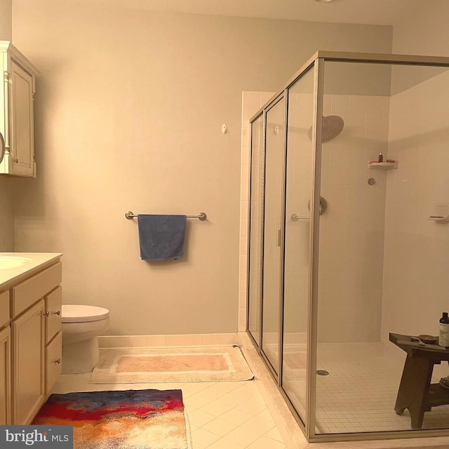 bathroom featuring tile patterned floors, vanity, toilet, and a shower with door