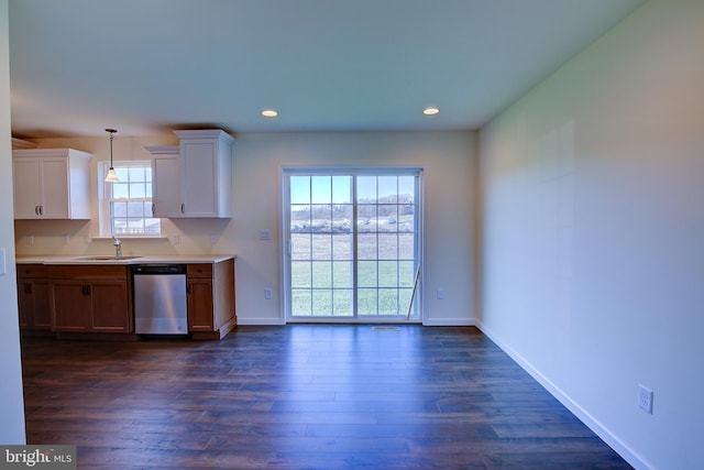 kitchen featuring dark wood-type flooring, baseboards, light countertops, and stainless steel dishwasher