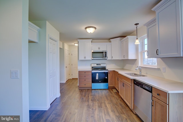 kitchen featuring stainless steel appliances, dark wood-type flooring, a sink, baseboards, and light countertops