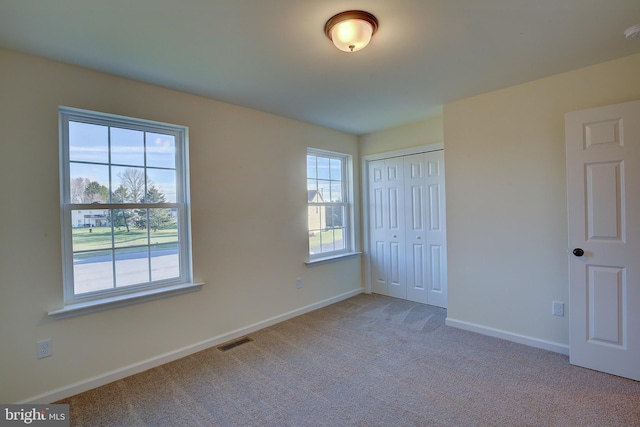 unfurnished bedroom with a closet, carpet, visible vents, and baseboards