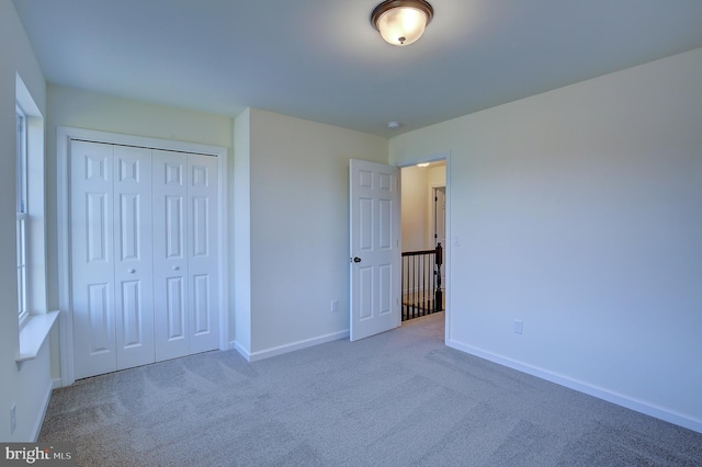 unfurnished bedroom with a closet, carpet flooring, and baseboards