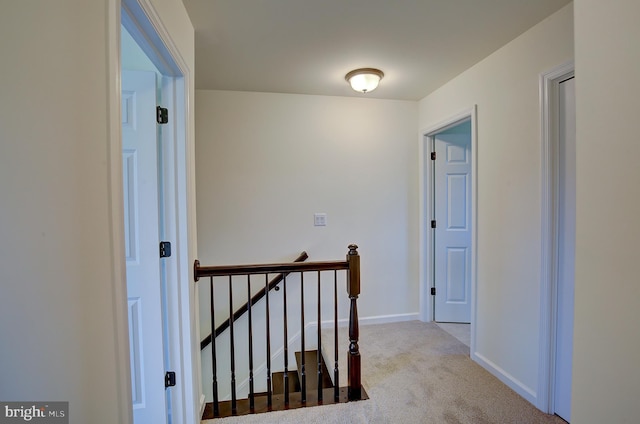 hallway with baseboards, carpet flooring, and an upstairs landing