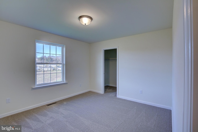 unfurnished bedroom featuring visible vents, baseboards, carpet, a spacious closet, and a closet