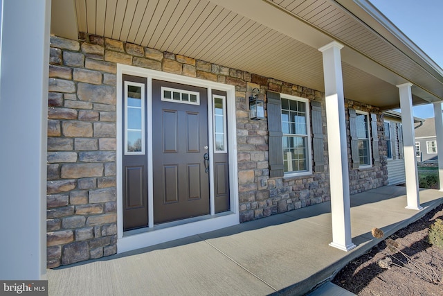 doorway to property featuring stone siding and a porch