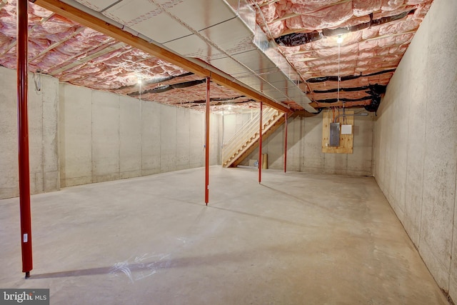 unfinished basement featuring electric panel and stairs