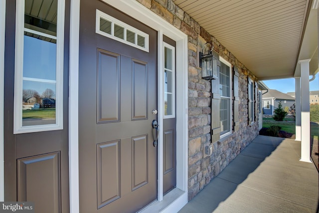 view of exterior entry featuring stone siding and a porch