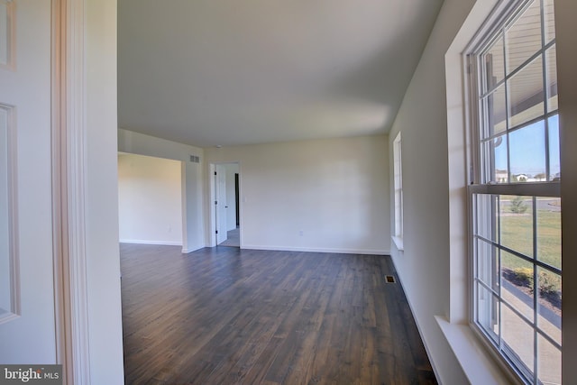 empty room with visible vents, dark wood finished floors, and baseboards