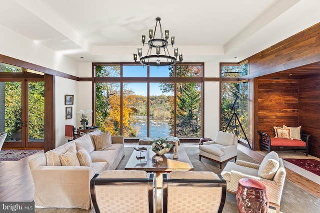 living room with plenty of natural light, an inviting chandelier, dark hardwood / wood-style flooring, and a water view