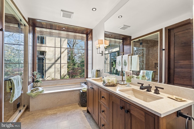 bathroom with tile flooring, dual sinks, vanity with extensive cabinet space, and a wealth of natural light