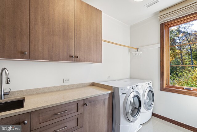 clothes washing area featuring cabinets, light tile floors, washer and dryer, and sink