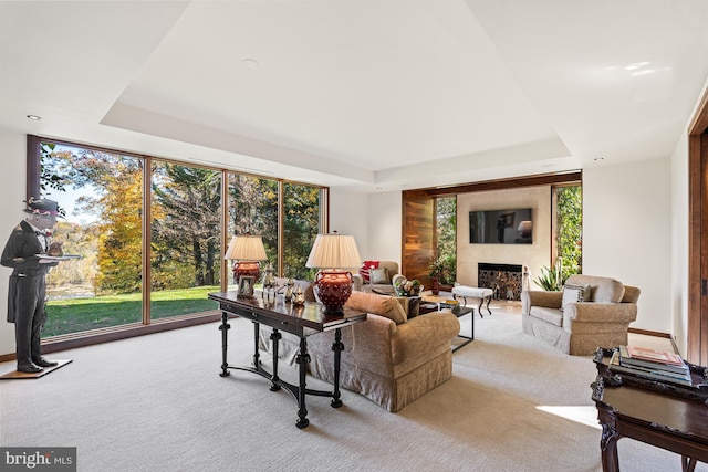 living room featuring light colored carpet, a raised ceiling, and floor to ceiling windows