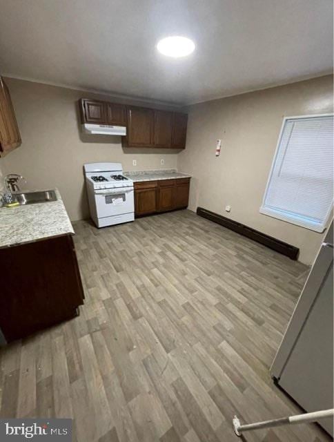 kitchen with dark brown cabinetry, white range with gas stovetop, sink, and light wood-type flooring