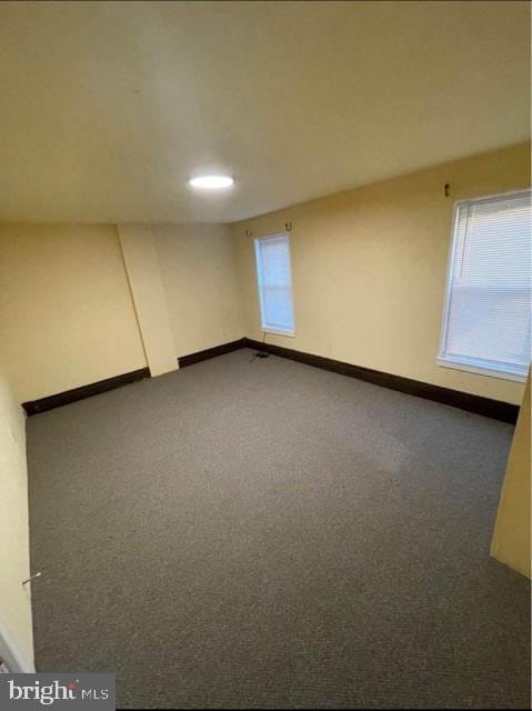 unfurnished room with dark colored carpet