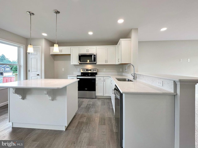 kitchen featuring appliances with stainless steel finishes, sink, decorative light fixtures, dark hardwood / wood-style floors, and white cabinetry