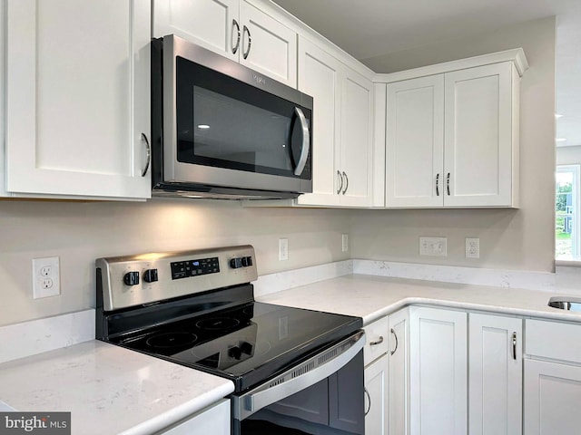 kitchen with appliances with stainless steel finishes, white cabinetry, and light stone countertops