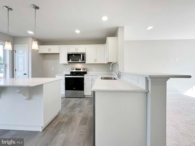 kitchen with hanging light fixtures, white cabinets, sink, carpet flooring, and appliances with stainless steel finishes