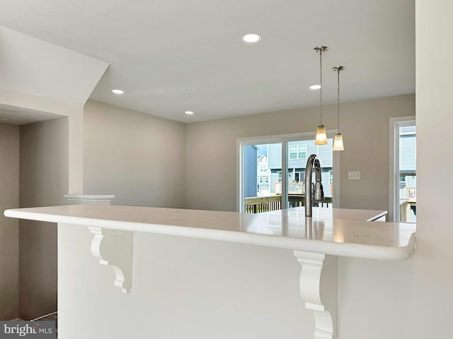 kitchen featuring sink, decorative light fixtures, a healthy amount of sunlight, and light stone counters