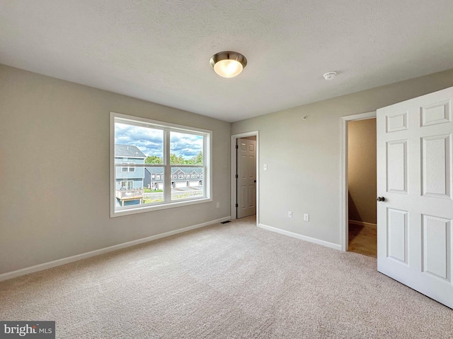 unfurnished bedroom with a textured ceiling and light colored carpet