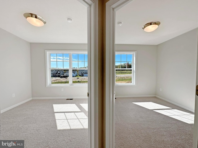 carpeted spare room featuring plenty of natural light