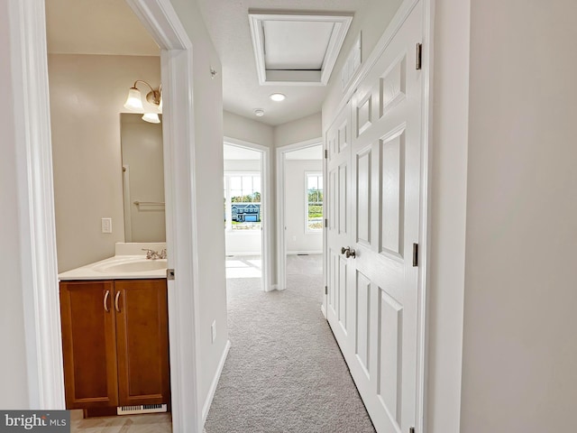 corridor featuring light carpet and sink