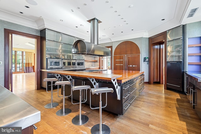 10111 Iron Gate Rd, Potomac, MD 20854 - kitchen featuring a kitchen breakfast bar, light hardwood / wood-style flooring, a center island, island range hood, and butcher block counters