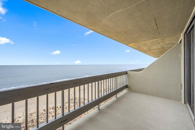 balcony with a water view and a view of the beach