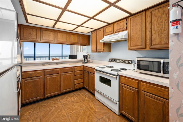 kitchen featuring dark tile flooring, refrigerator, white electric range oven, and a water view