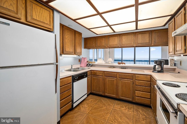 kitchen with white appliances, sink, dark tile flooring, extractor fan, and a water view