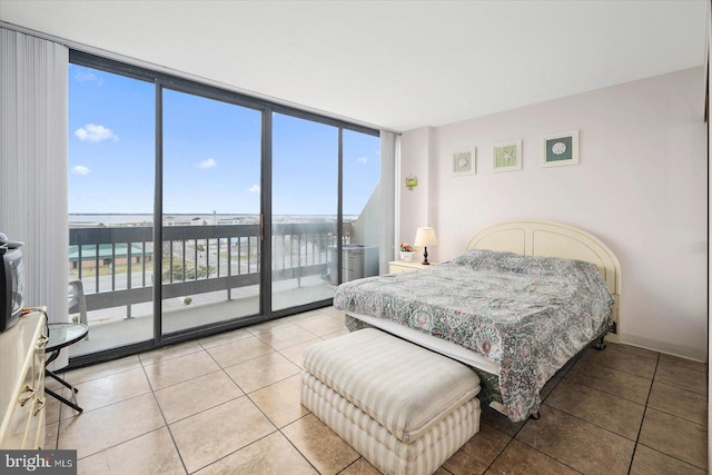 bedroom featuring multiple windows, a water view, light tile flooring, and expansive windows