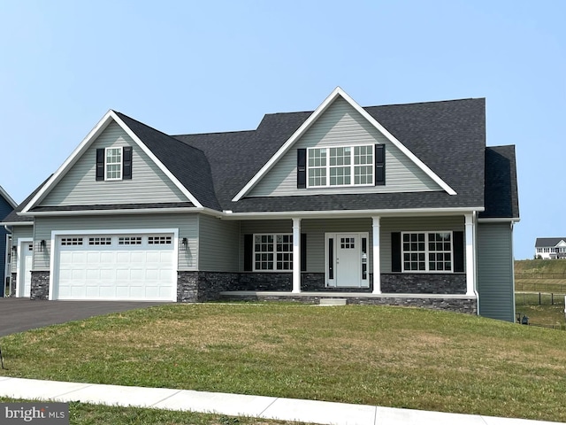 view of front of house featuring a front yard, covered porch, and a garage