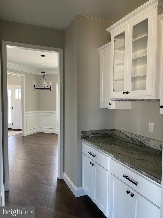 kitchen with an inviting chandelier, dark hardwood / wood-style flooring, white cabinetry, and stone counters