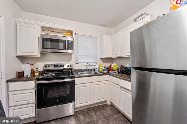 kitchen featuring sink, stainless steel appliances, white cabinetry, and dark tile flooring