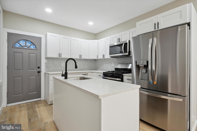 kitchen featuring backsplash, light hardwood / wood-style floors, stainless steel appliances, and sink