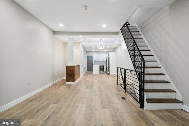 interior space featuring a tray ceiling, a chandelier, and light hardwood / wood-style flooring