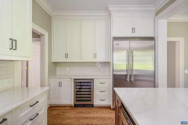 kitchen with wine cooler, tasteful backsplash, hardwood / wood-style floors, stainless steel built in fridge, and light stone countertops