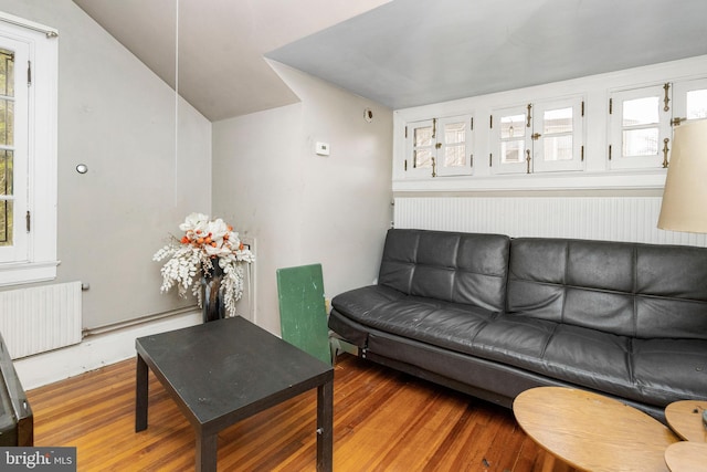 living room featuring lofted ceiling, radiator heating unit, and hardwood / wood-style flooring