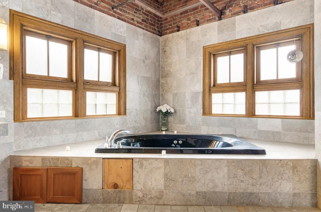 bathroom with plenty of natural light, a relaxing tiled bath, brick ceiling, and tile walls